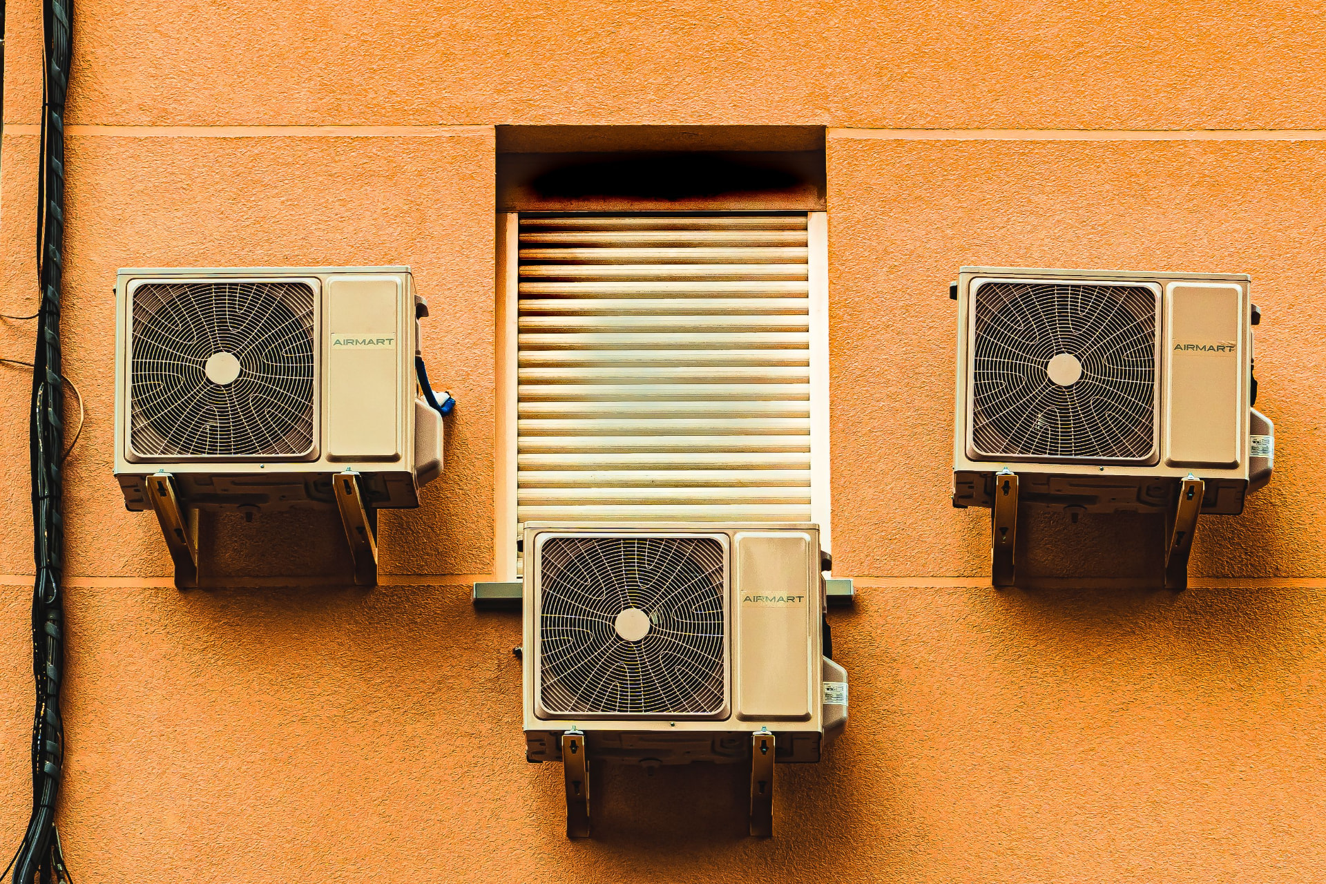 Three outdoor HVAC units mounted on an orange building